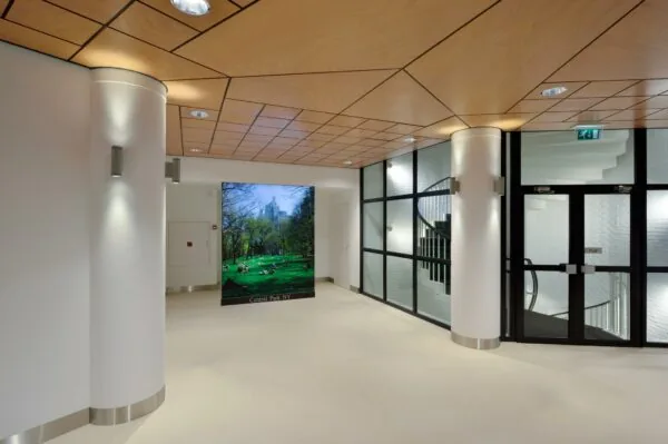 Moderne gang in een gebouw aan de Floris Grijpstraat met houten plafond, witte muren en een grote foto van Central Park, NY.